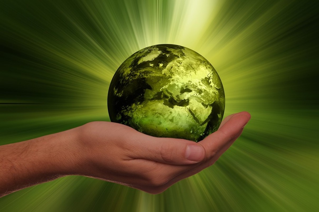 Eine offene Hand hält eine kleine, grüne Weltkugel.