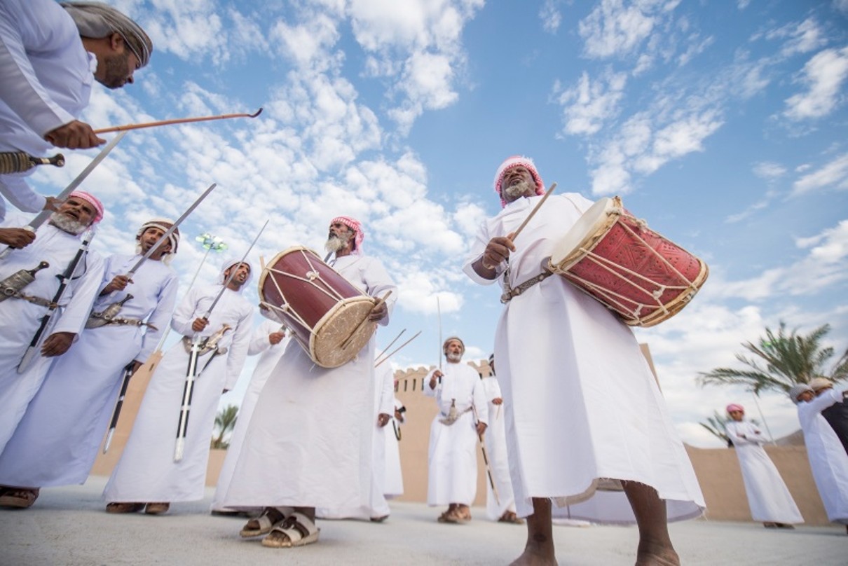tanzende Omanis in einer weißen Dishdasha mit Trommeln in der Hand