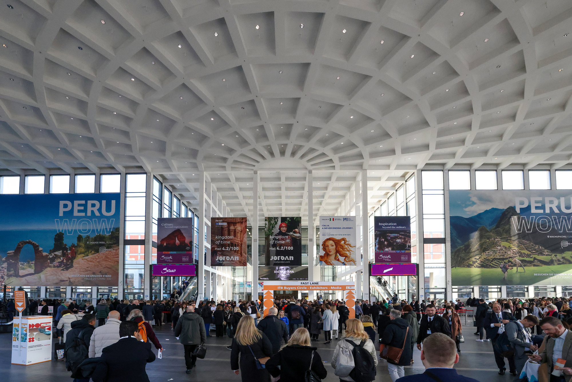 Menschen in der Eingangshalle der ITB Berlin, im Hintergrund Werbeplakate. 