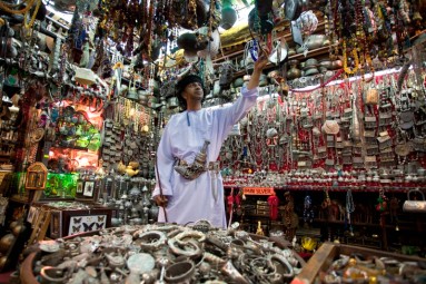 Ein Omani an einem Schmuckstand auf dem Souk von Mutrah, umgeben von Schmuck
