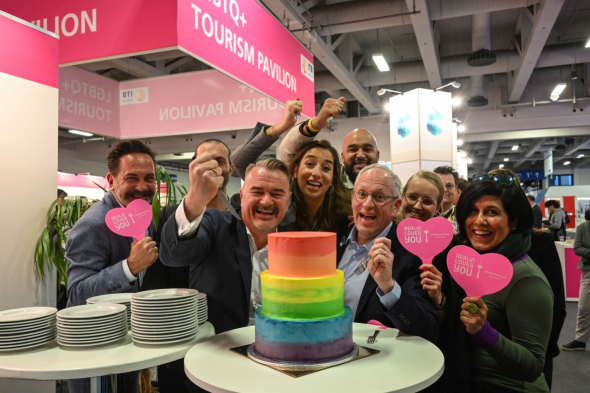  LGBTQ+ Team vor einer Regenbogen Torte 