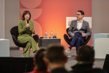 Das Bild zeigt zwei Personen auf einer Bühne, die an einer Podiumsdiskussion teilnehmen
