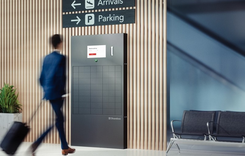 A person walking towards a Sharebox that is located in an airport. 