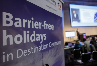 A banner reading ‘Barrier-free holiday in Destination Gemany’, with people sitting in the background out of focus. 