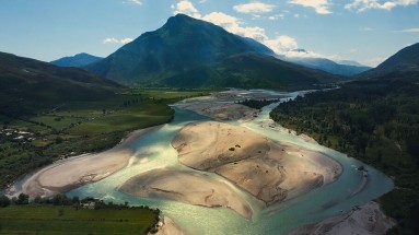 Vjosa River delta, with a mountain landscape and green fields in the background. 