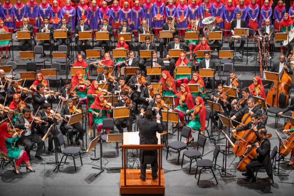 The musicians of the Royal Oman Symphony Orchestra during a performance, with the conductor in the foreground. 