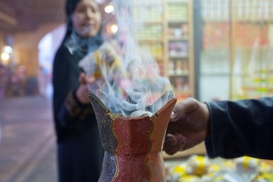 Rising smoke from an incense burner, in the background a woman looks at the smoke.