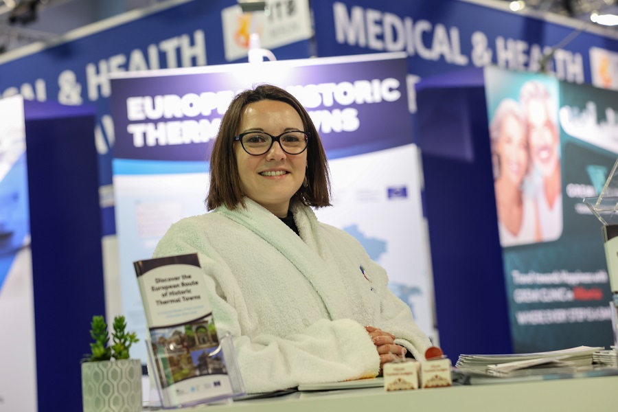 A woman in a bathrobe at a trade show stand looking into the camera. A woman in a bathrobe at a trade show stand looking into the camera.