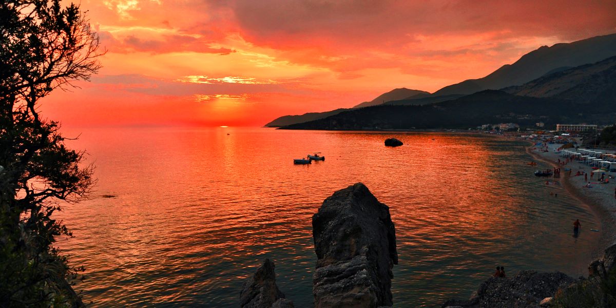 A bay at the Albanian coast. In the background a sunset lights up the sky in red. A bay at the Albanian coast. In the background a sunset lights up the sky in red.