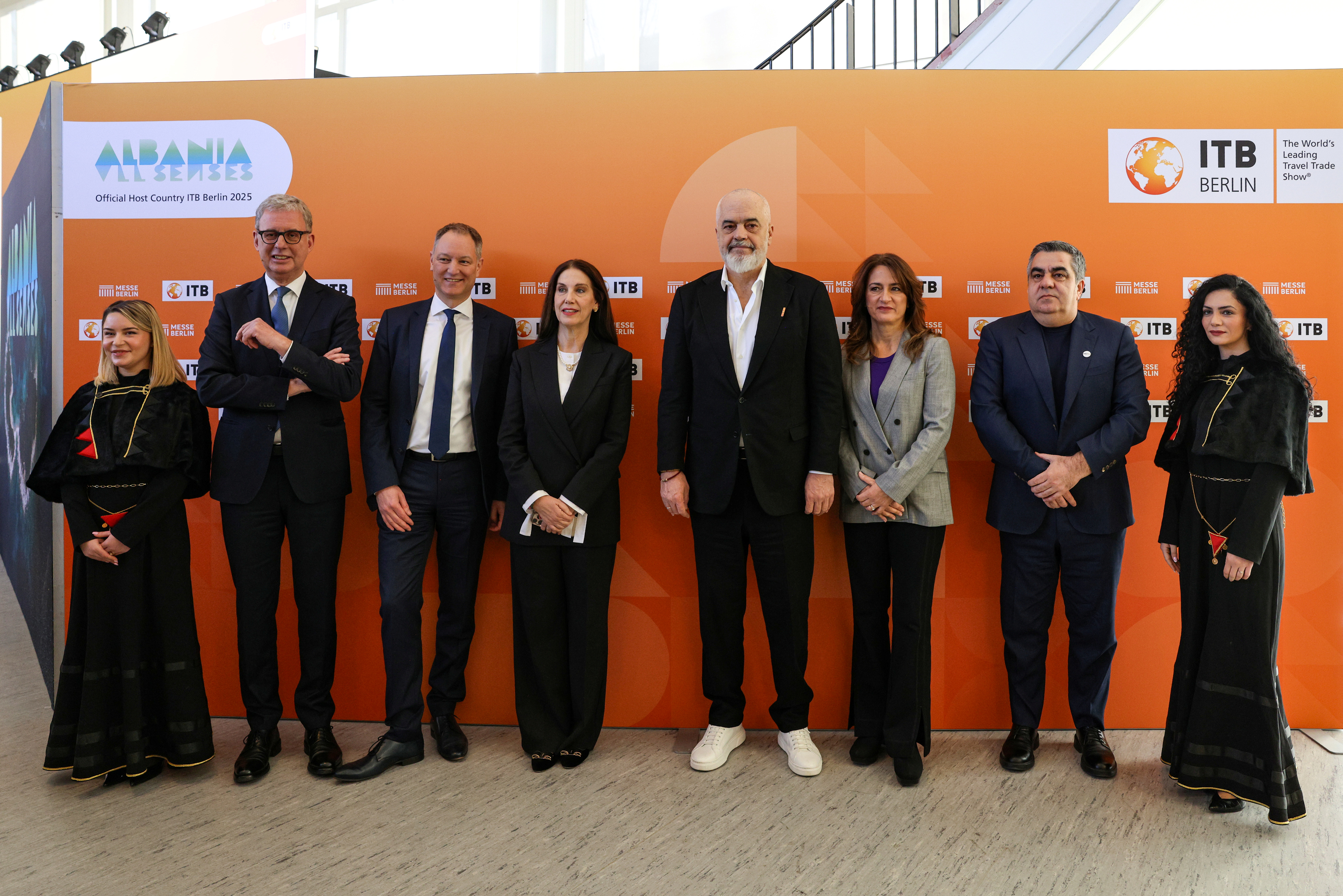 Eine Gruppe von acht Personen posiert vor einer ITB-Berlin-Wand mit 'Albanien'-Branding.